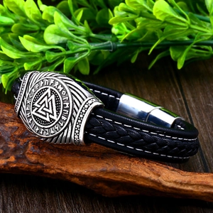 Detail of Viking Valknut leather bracelet with engraved Nordic runes on aged wood