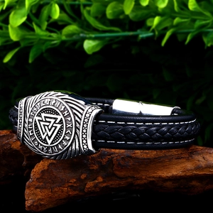 Macro shot of black leather Viking bracelet with silver Valknut charm on wood