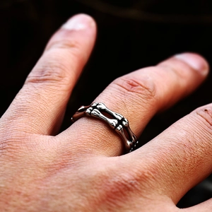 Gros plan d'une bague punk en forme d'os de squelette en argent vieilli au doigt