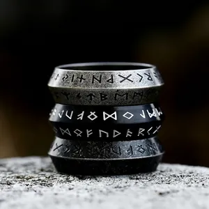 Three stacked vintage stainless steel rings with engraved runes on a natural stone base