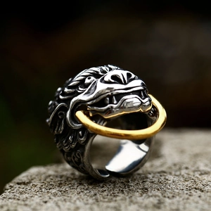 Vintage stainless steel lion head ring with movable gold hoop on a stone surface