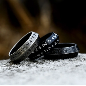 Close-up of vintage Viking rune rings in silver, matte black and grey on rustic rock