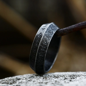 Macro shot of vintage silver Viking rune ring with engraved Nordic symbols on steel