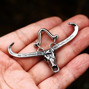 Vintage stainless steel bull skull pendant held in hand showing antique texture and details