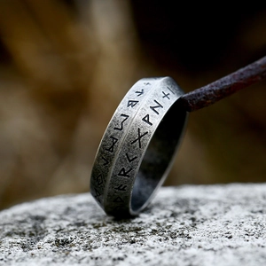 Macro shot of Nordic Elder Futhark runes engraved on vintage oxidized steel ring band