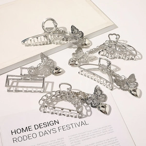 Detailed view of silver metal hair claws with butterfly and heart chain pendants