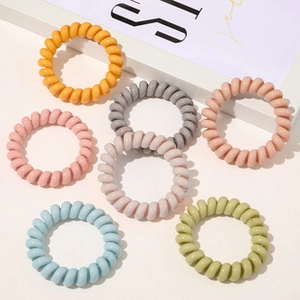 Detailed close-up of macaron-colored spiral hair ties in 7 various pastel shades