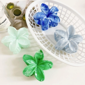 Detail view of marble-textured floral hair claws in blue and green shades