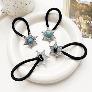 Close-up of bohemian silver star hair ties with turquoise inlay on a ceramic tray