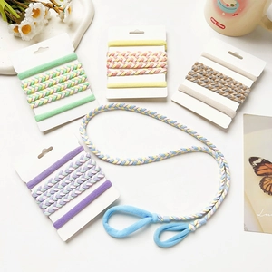 Détail de l'ensemble bandeau tressé coloré et élastiques à cheveux sur un bureau blanc