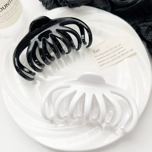 Top view of large black and white glossy resin hair claws in a decorative white plate
