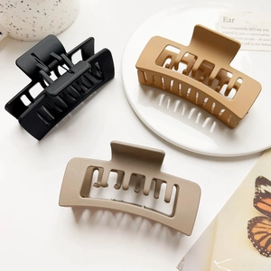 Three large matte square hair claws in black, khaki, and brown shown in a lifestyle setting