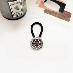 Detail of bohemian hair tie featuring vintage alloy ornament with a red center bead