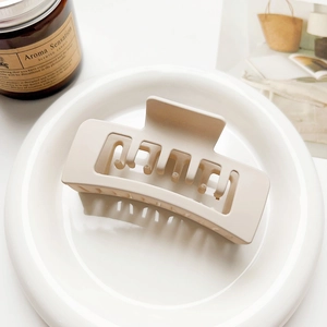 Close-up of a large matte rectangular hair claw clip in a soft beige milk tea color