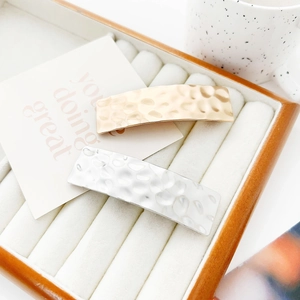 Detail view of rectangular metal hair clips with gold and silver hammered textures