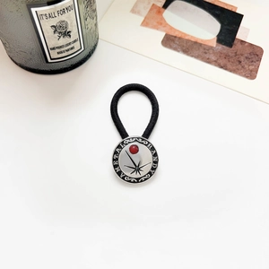 Detail of vintage silver hair tie with red bead inlay and engraved metal charm on white background