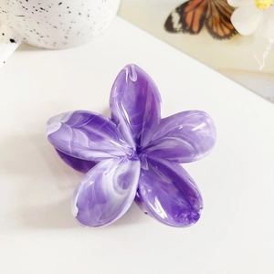 Close-up of marble textured purple frangipani flower hair claw on a ceramic mug background