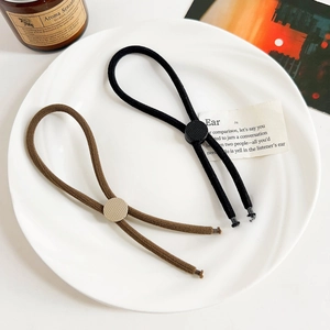 Detail of adjustable minimalist hair ties in black and brown with metallic slide beads
