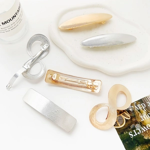 Detail view of gold and silver geometric spring hair clips with brushed metal finish