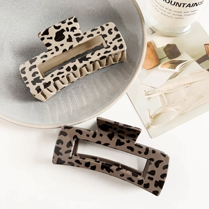 Close-up of leopard print hair claws in cream and taupe on a ceramic tray