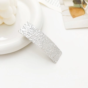 Detailed view of silver metallic hair clip with unique irregular hammered texture finish