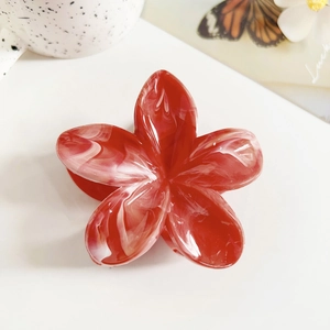 Detail of plumeria hair claw clip with red and white marble resin texture on flower petals