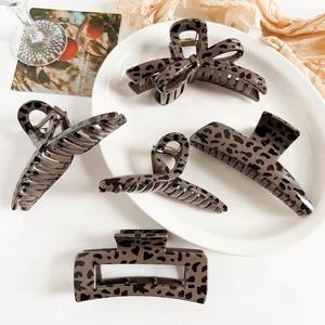 Detail view of leopard print claw clips in various shapes with a vintage coffee-toned pattern
