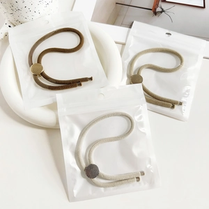 Detailed view of elastic hair bands in neutral tones with textured metal sliders in packaging