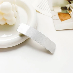 Detailed view of silver rectangular hair clip with vertical brushed metal texture