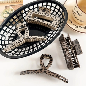 Detail of four leopard print hair claws in rectangle and curved shapes with metal springs