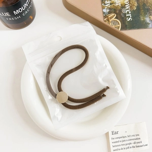 Detailed view of a brown elastic hair tie with a textured gold round buckle on a plate