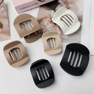 Detailed close-up of matte claw hair clips in black, brown, beige, and cream colors