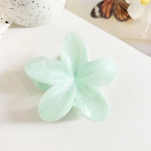 Detail of light green plumeria hair claw clip with a glossy jade-like resin finish