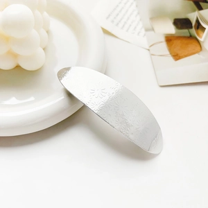 Detailed view of silver hair clip featuring laser-engraved daisy floral patterns