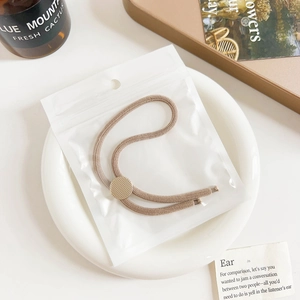 Close-up of earth-toned braided hair tie with a textured gold metal buckle in a dish