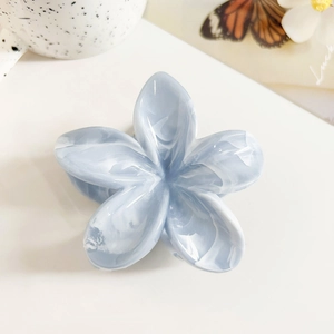 Macro view of a light blue marble-textured frangipani hair claw with high-quality finish