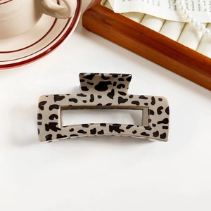 Detailed view of leopard print hair claw clip with glossy resin finish on wooden tray