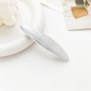 Detail of silver metallic geometric spring hair clip with fine brushed texture finish