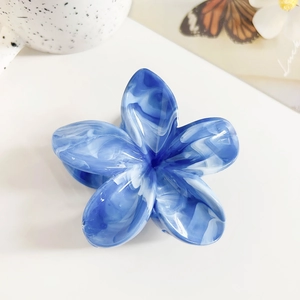 Detailed macro view of a blue marble-patterned frangipani flower hair claw clip