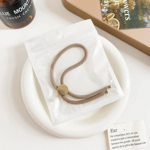 Detail view of khaki threaded hair tie with golden metal slider buckle on ceramic tray