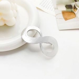 Detailed macro view of silver infinity shaped metal hair clip with brushed texture finish