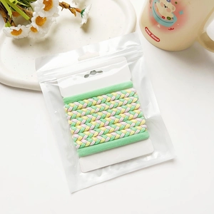 Détail d'élastiques tressés colorés aux tons macaron présentés sur carte