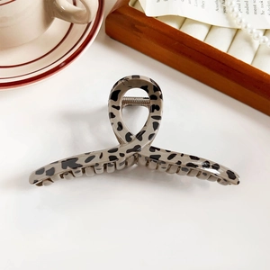 Detail of a glossy leopard print hair claw clip on a stylish table with pearls