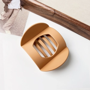 Macro view of matte caramel brown hair claw clip with modern minimalist hollow design