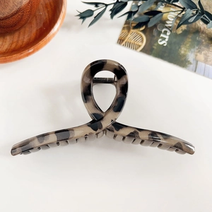 Détail de la grande pince à cheveux léopard avec texture écaille et design de torsion