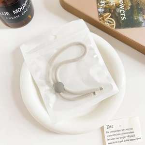 Detail of cream elastic hair tie with silver button in clear polybag on ceramic plate