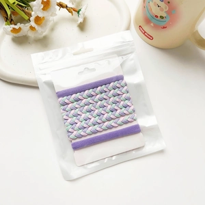 Détail de 7 chouchous tressés colorés présentés dans un sac de vente transparent