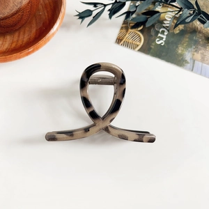 Détail d'une pince à cheveux léopard avec design croisé et mécanisme à ressort métal