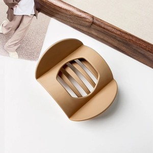 Detailed view of matte caramel hair claw clip with cutout design on a wooden background