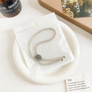Close-up of adjustable threaded hair tie with textured silver metal disc in packaging
